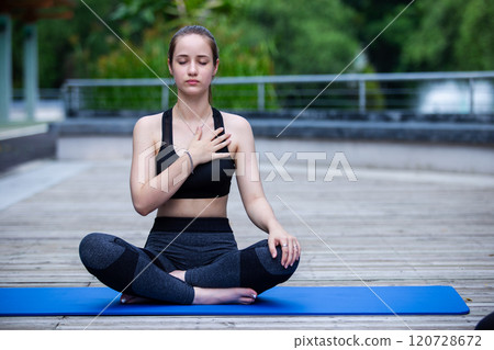 Beautiful women sportswear practicing yoga sitting pose stretching legs and folded hands. Prayer position yoga outdoor on floor. Relaxation yoga exercise concept. 120728672