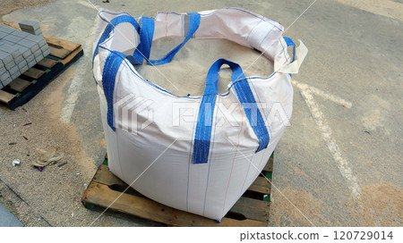Large bag of cement mix prepared for street repair work in urban area during daylight hours 120729014