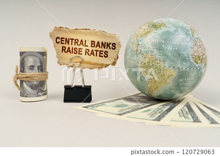 On the table are dollars, a globe and there is a sign with the inscription - Central banks raise rates On the table are dollars, a globe and there is a sign with the inscription - Central banks raise rates 120729063