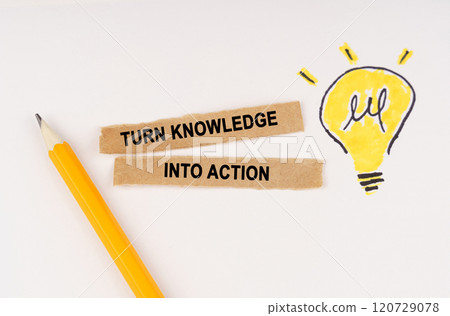 On a white surface, a luminous light bulb and pieces of paper with the inscription - turn knowledge into action 120729078