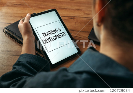 A woman holds a tablet in her hands on the screen of which it is written - Training and Development 120729084