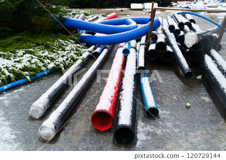 Blue, black and red pipelines of various diameters lie on a construction site outdoors in winter. 120729144