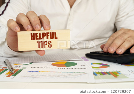 On the table are business charts and diagrams in the hands of a wooden block with the inscription - Helpful Tips On the table are business charts and diagrams in the hands of a wooden block with the inscription - Helpful Tips 120729207