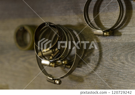 On the wall in the garage, metal clamps hang on self-tapping screws. On the wall in the garage, metal clamps hang on self-tapping screws. 120729242
