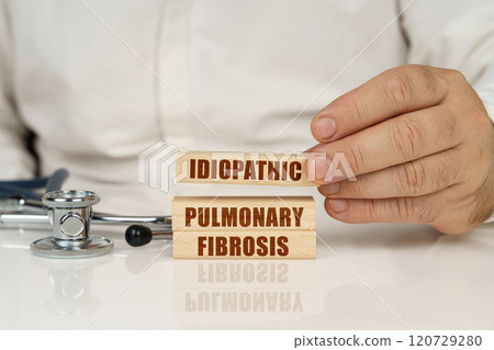 On a white surface, a stethoscope and wooden plates with the inscription - Idiopathic pulmonary fibrosis On a white surface, a stethoscope and wooden plates with the inscription - Idiopathic pulmonary fibrosis 120729280