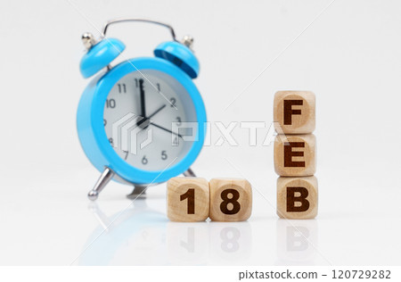 On a white background, a blue alarm clock and a calendar with the inscription - February 18 On a white background, a blue alarm clock and a calendar with the inscription - February 18 120729282