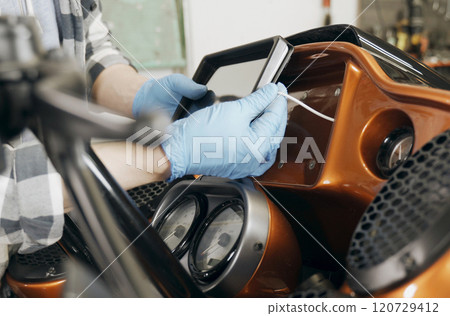 The mechanic installs a tablet on a motorcycle. The mechanic installs a tablet on a motorcycle. 120729412