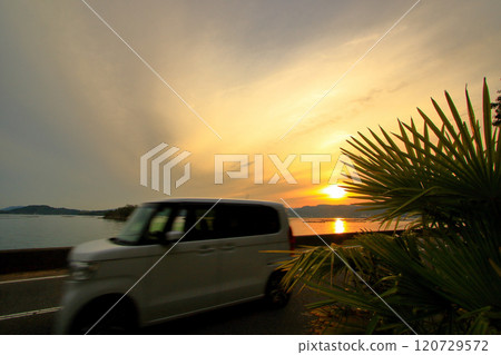 黃昏時分，一輛汽車沿著海岸行駛 120729572