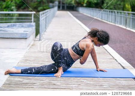 Sporty fit american african women sportswear performing asana yoga, Pose Outdoor active workout. Strong female healthy lifestyle. Relax yoga exercise concept. Sporty fit american african women sportswear performing asana yoga, Pose Outdoor active workout. Strong female healthy lifestyle. Relax yoga exercise concept. 120729668