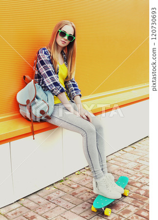 Fashion pretty blonde girl with skateboard over colorful orange background Fashion pretty blonde girl with skateboard over colorful orange background 120730693