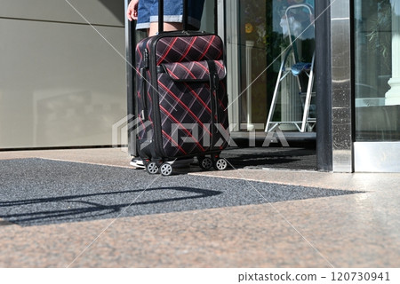 Joyful man in a cloak and his elegant wife arriving at a hotel with their luggage 120730941
