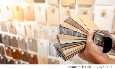 Designer hand choosing sample of wood laminated from natural collection in material showroom Designer hand choosing sample of wood laminated from natural collection in material showroom 120732387