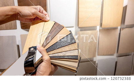 Designer hand picking sample of wood laminated from natural collection in material showroom 120732388