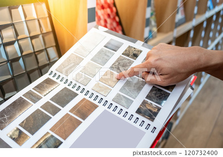 Customer hand pointing at sample of stone tile swatch collection in material catalog Customer hand pointing at sample of stone tile swatch collection in material catalog 120732400