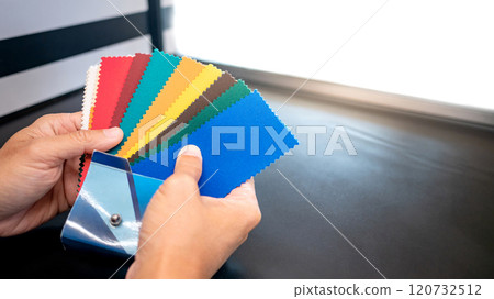 Fabric swatch material choice. Designer hand choosing fabric sample pieces from color collection Fabric swatch material choice. Designer hand choosing fabric sample pieces from color collection 120732512