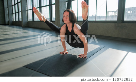 Yoga practice. Balance workout. Athletic woman in activewear doing gymnastic training exercise handstand frog pose asana on sport mat in gym fitness studio indoors. Yoga practice. Balance workout. Athletic woman in activewear doing gymnastic training exercise handstand frog pose asana on sport mat in gym fitness studio indoors. 120732932