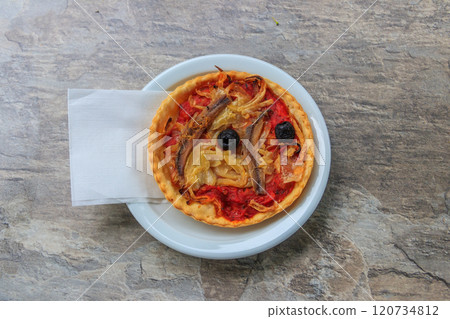 Tasty quiche with anchovies, olives, onion and tomato sauce on a table. French food Tasty quiche with anchovies, olives, onion and tomato sauce on a table. French food 120734812