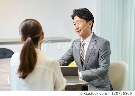 A man in a suit talking to a woman A man in a suit talking to a woman 120736509
