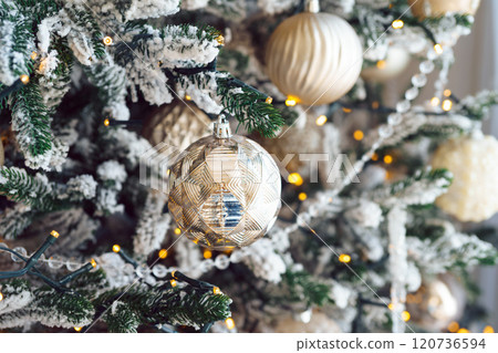 Christmas tree with frosted snowy branches decorated with silver and gold ornaments with lights 120736594
