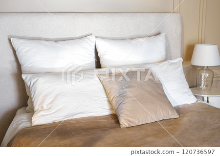 Cozy bedroom setting with plush pillows and soft bedding during daylight hours Cozy bedroom setting with plush pillows and soft bedding during daylight hours 120736597