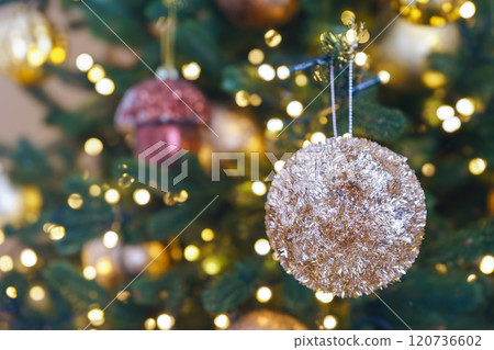Decorated Christmas tree with golden festive ornaments on shining lights garland background Decorated Christmas tree with golden festive ornaments on shining lights garland background 120736602