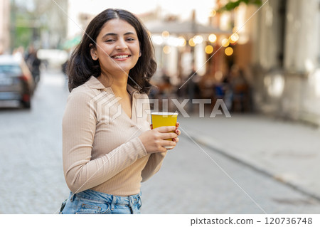 Happy Indian woman enjoying drinking morning coffee hot drink relaxing taking a break on city street Happy Indian woman enjoying drinking morning coffee hot drink relaxing taking a break on city street 120736748