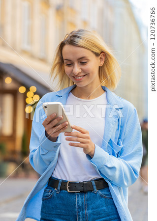 Happy woman using smartphone typing texting social media application messages e-mail on city street Happy woman using smartphone typing texting social media application messages e-mail on city street 120736766