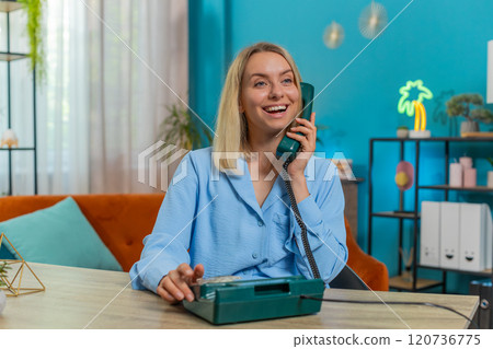 Woman freelancer working, talking with client on retro old-fashioned wired telephone at home office Woman freelancer working, talking with client on retro old-fashioned wired telephone at home office 120736775
