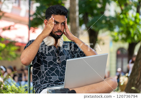 Hispanic sad young man using laptop receive bad email message news, game fail in urban city street 120736794