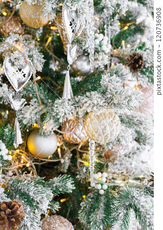 Christmas tree with frosted snowy branches decorated with silver and gold ornaments with lights 120736908