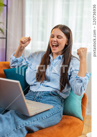 Surprised happy young woman using laptop computer, receive good news email message at home room 120736936