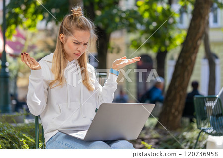 Young woman using laptop loses becoming surprised by sudden lottery results loss, fail in street Young woman using laptop loses becoming surprised by sudden lottery results loss, fail in street 120736958