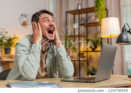 Frustrated freelancer using laptop struggling to work due to loud noise sitting at home office table Frustrated freelancer using laptop struggling to work due to loud noise sitting at home office table 120736959