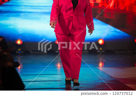 An unrecognizable overweight female model shows off a costume on the catwalk. 120737012
