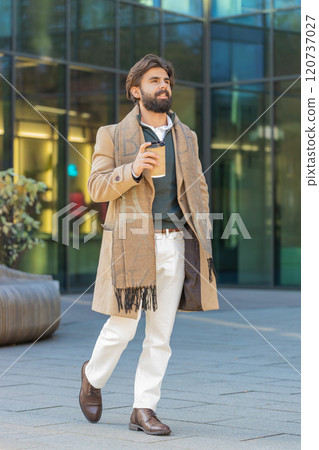 Happy Indian business man tourist enjoying morning coffee hot drink walking on city downtown street Happy Indian business man tourist enjoying morning coffee hot drink walking on city downtown street 120737027