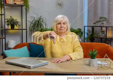 Upset senior woman showing thumbs down, dislike bad work, disapproval, dissatisfied feedback at home Upset senior woman showing thumbs down, dislike bad work, disapproval, dissatisfied feedback at home 120737259