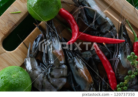 A beautiful display of tiger shrimp rests on banana leaves, accompanied by green limes and red chili peppers. A beautiful display of tiger shrimp rests on banana leaves, accompanied by green limes and red chili peppers. 120737350