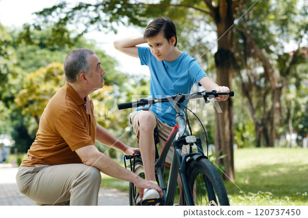 Grandfather Teaching His Grandchild To Ride A Bike Grandfather Teaching His Grandchild To Ride A Bike 120737450