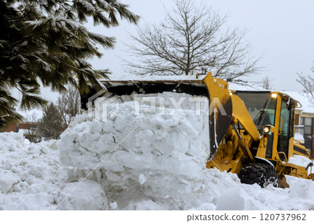 Snow is being cleared from parking lot residential street by yellow snow plow in winter snowy day setting. Snow is being cleared from parking lot residential street by yellow snow plow in winter snowy day setting. 120737962