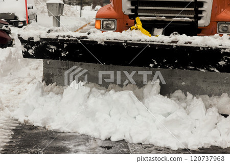 Snow plow is actively removing thick layers of snow from parking lot residential streets in winter setting. 120737968