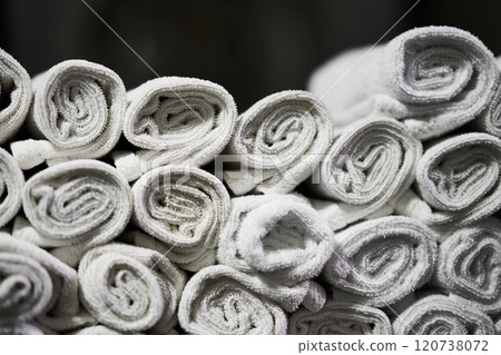 Neatly rolled white towels stacked in a laundry facility for organized storage 120738072