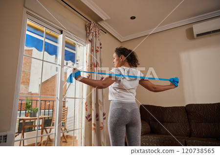 Woman doing resistance band workout at home by the window 120738565