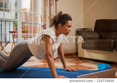Woman practicing yoga at home in living room setting 120738600