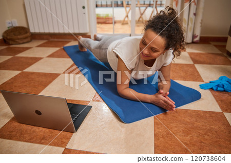 Woman doing online workout at home on yoga mat 120738604