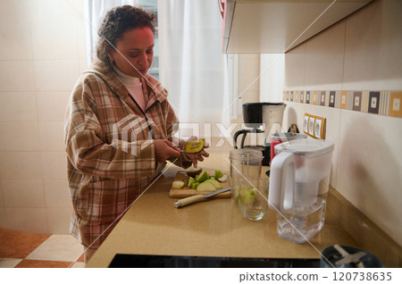 Woman preparing healthy fruit snack in cozy kitchen Woman preparing healthy fruit snack in cozy kitchen 120738635