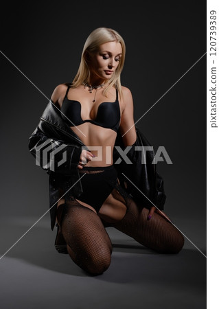 Woman posing in black lingerie and leather jacket against dark background Woman posing in black lingerie and leather jacket against dark background 120739389