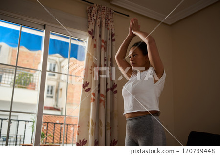 Woman practicing yoga at home in a serene indoor setting Woman practicing yoga at home in a serene indoor setting 120739448