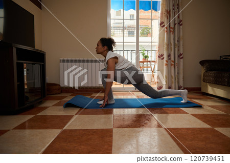 Woman practicing yoga indoors with natural light and focus 120739451