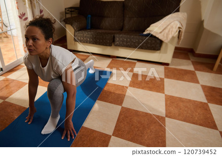 Woman practicing yoga on mat in cozy living room 120739452