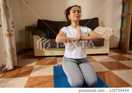 Peaceful yoga meditation at home on a blue exercise mat Peaceful yoga meditation at home on a blue exercise mat 120739459